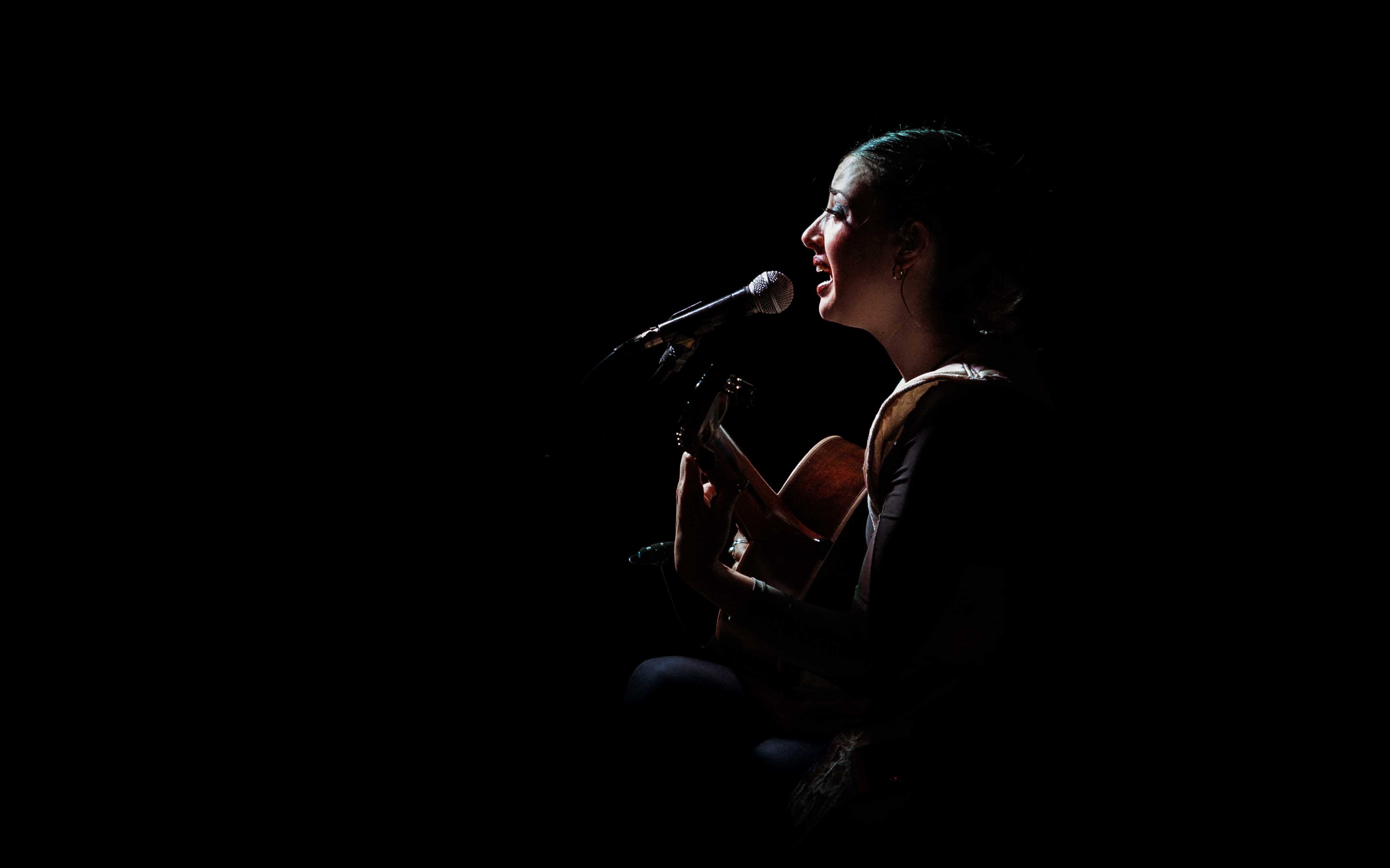 María tocando guitarra acústica durante el concierto