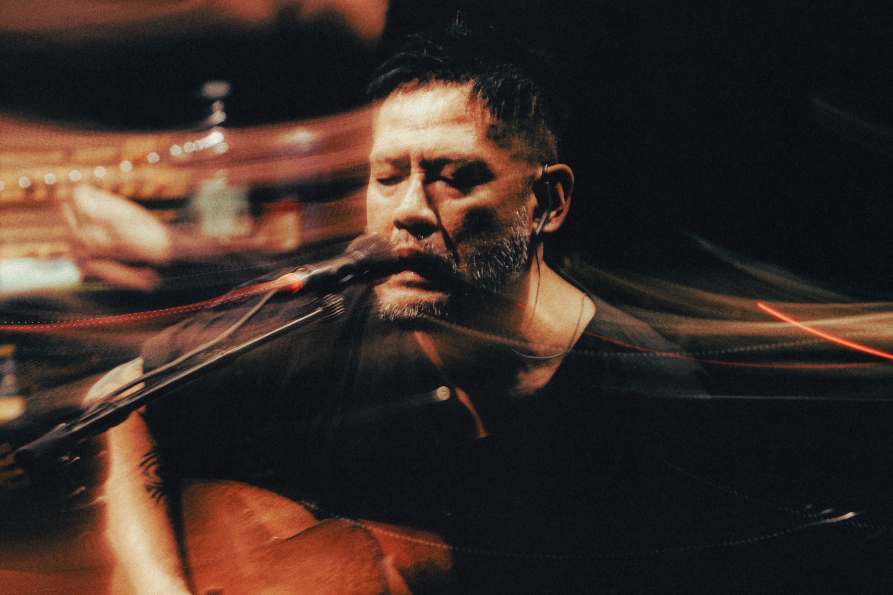 Hirokazu Yamazaki cantando y tocando guitarra con estelas de luz
